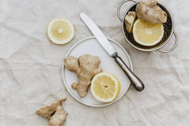 Ginger roots with lemon flat lay on linen tablecloth. Healthy organic food  clipart