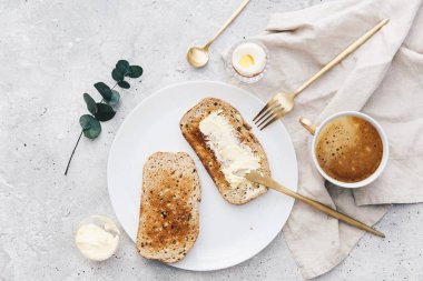 Ekmek dilimleri ile bitişik tereyağı ve tereyağı bıçağı üzerinde rustik keten masa örtüsü . 