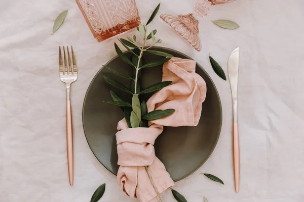 Rustic table setting. Table decorations with linen napkin, olive branch. Top view. Flat lay.  Wedding or holiday concept