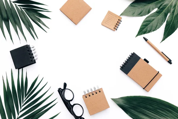 Minimal Office desk table with stationery set, supplies and palm leaves. Top view with copy space, creative flat lay.