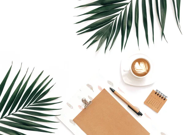 Minimal Office desk table with stationery set, supplies and palm leaves. Top view with copy space, creative flat lay.