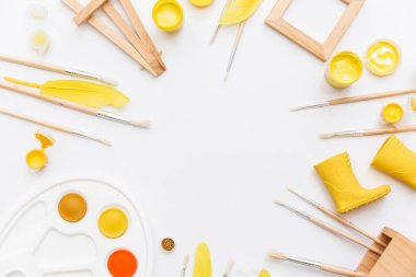 Sanatçı çalışma alanı boyalar, boya fırçaları, beyaz zemin üzerine sarı tüyleri ile