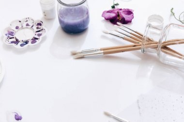 Beyaz arka plan üzerinde sanatçı çalışma alanı ile boyalar, palet, Boya fırçaları