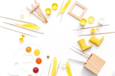 Sanatçı çalışma alanı boyalar, boya fırçaları, beyaz zemin üzerine sarı tüyleri ile