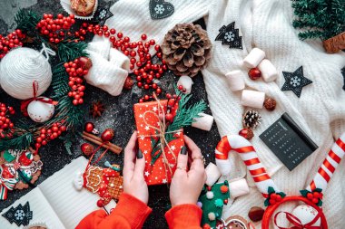 Kadın eli, içinde süslemeler olan bir Noel hediyesi olan bir kutuyu tutuyor. Noel, Noel, Noel, kış, yeni yıl, sıfır atık kavramı. Düz konum, üst görünüm, kopyalama alanı, arkaplan