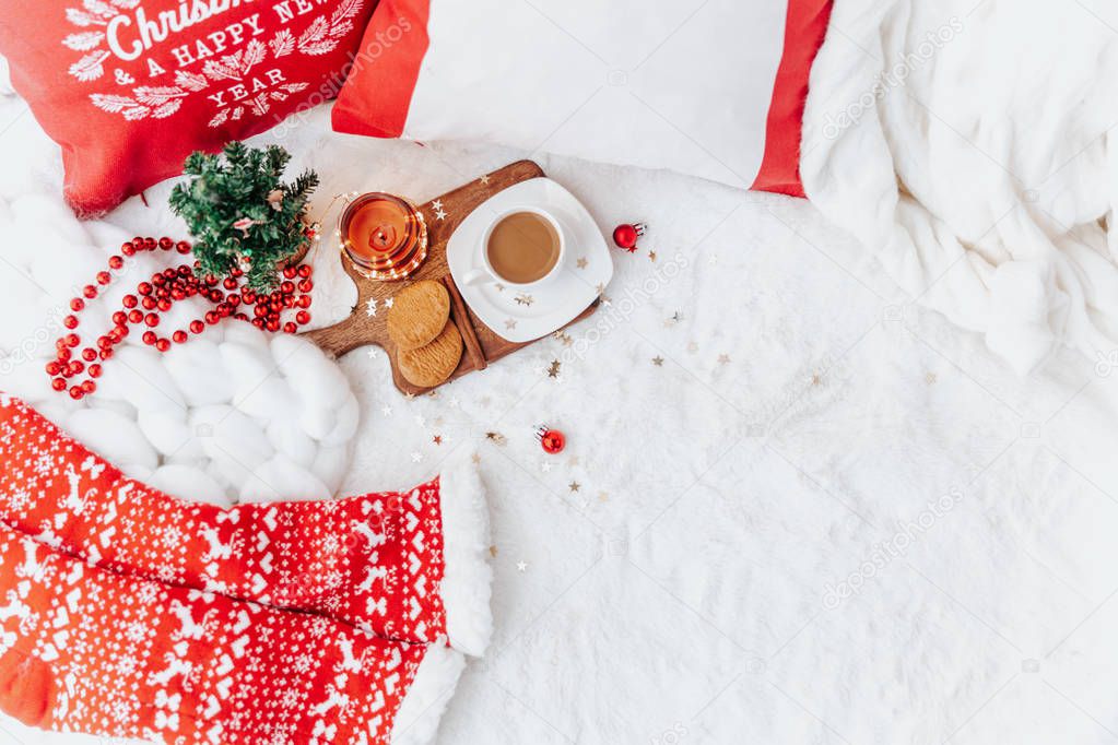 Winter composition with coffee on the bed. Cup of coffee on wooden tray. Festive cozy concept. Flat lay, top view 