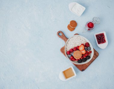 Düz Yulaf ezmesi ve mavi arka planda kahvaltı için böğürtlen kasesi. Sağlıklı gıda konsepti. Üst görünüm 