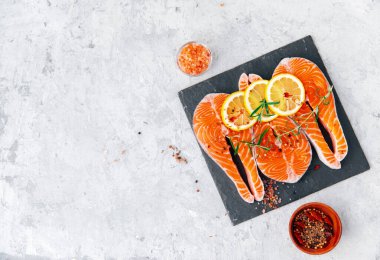 Siyah masada tuz ve limon ve bitkilerle birlikte bir parça somon.