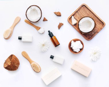 Beyaz arka planda hindistan cevizi parçaları ve vücut bakım ürünleriyle organik sağlıklı hindistan cevizi ezmesi.