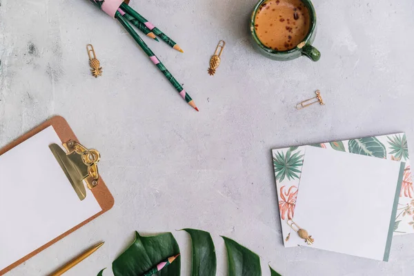 Minimal Office desk table with stationery set, supplies and monstera leaves. Top view with copy space, creative flat lay