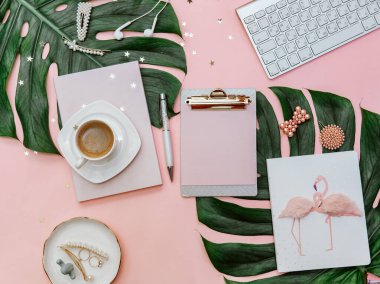Kadınsı düz yatak, blogcular için tropikal pembe arka plan üzerine pano, pastel pembeli modern ofis masası, kahve fincanı ve kırtasiye malzemesi..