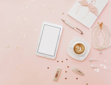 Pembe arka planda ofis çalışma alanı. Kahve ve defter blogger konsepti. Tablet ve kadın aksesuarlarıyla yatıyordu.