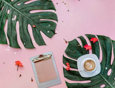 Kadınsı yaratıcı tasarım çalışma alanı. Kahve, pembe arka planda tropikal yapraklar, blog yazarı kavramı