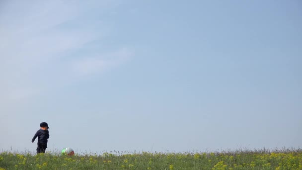 Malý chlapeček hraje s velkým míč na hřebenu kopce, klidnou oblohu nad 4k