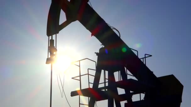Oil pump fossil fuel extraction hydraulic drilling rig unit silhouette with sun rays in background on industrial platform