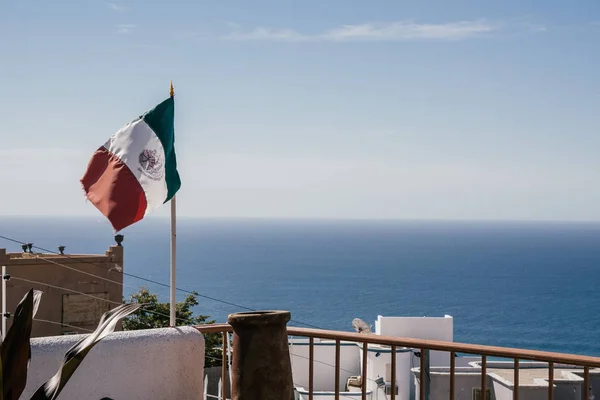 Meksika'nın bir okyanus manzarası ve mavi gökyüzü önünde bayrak sallayarak