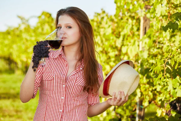 葡萄的领域里拿着一杯红酒的年轻快乐的女人 — 图库照片