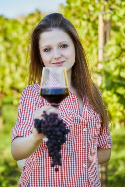 葡萄的领域里拿着一杯红酒的年轻快乐的女人 — 图库照片