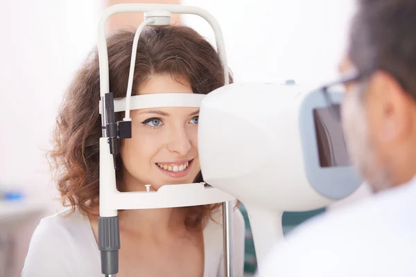 Optometrista in sala esami con donna in sedia — Foto Stock