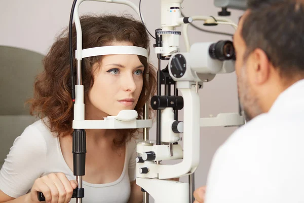 Optometrista in sala esami con donna in sedia — Foto Stock