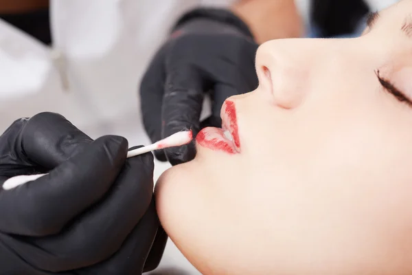 Cosmetologist applying permanent make up on lips