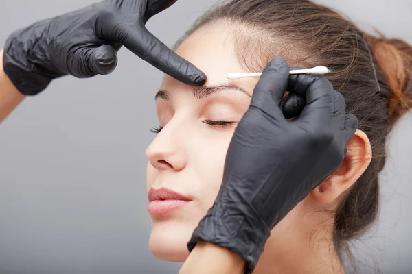 Cosmetologist aplicando a composição permanente nas sobrancelhas — Fotografia de Stock