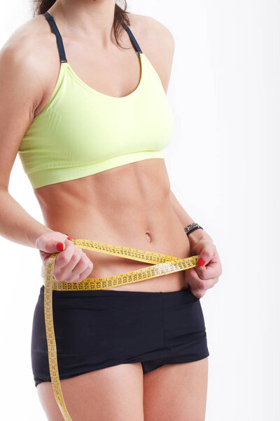 Slim young woman measuring her thin waist with a tape measure, close up