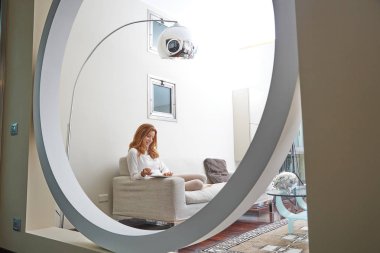 Genç kız kanepede oturup internetten alışveriş yapmayı düşünüyor.