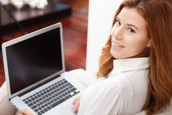 Leende lycklig kvinna sitter på soffan och använder laptop — Stockfoto