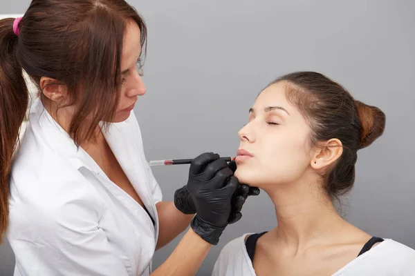 Cosmetologue appliquant un maquillage permanent sur les lèvres — Photo