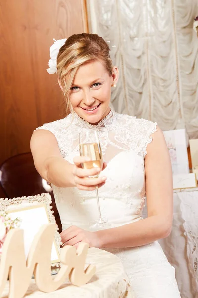 Vrolijke bruid een champagne glas glimlachend in de camera te houden — Stockfoto