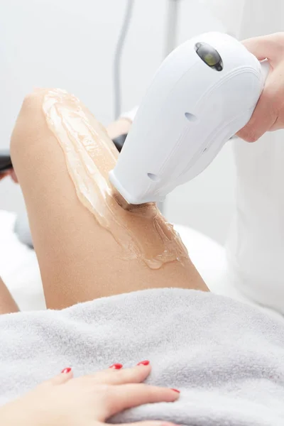 Kosmetyczka poddająca depilację laserową kobiecie na udzie — Zdjęcie stockowe