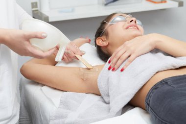 Young woman having underarm laser hair removal treatment in salon clipart