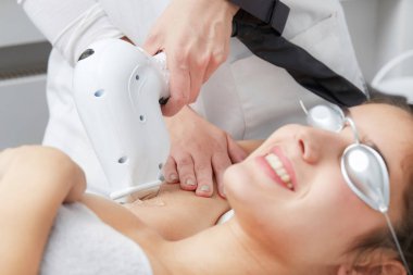 Young woman having underarm laser hair removal treatment in salon clipart