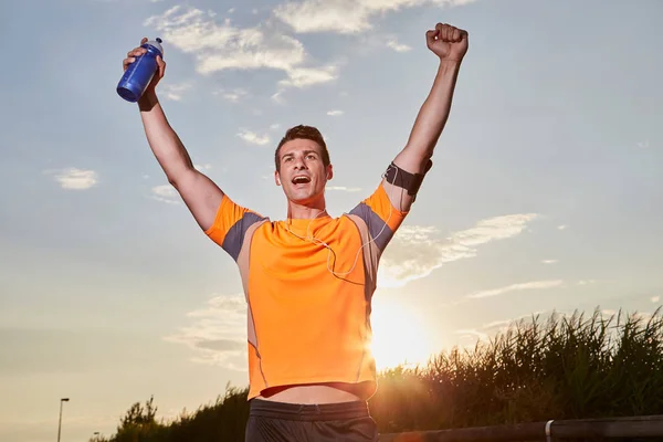 Hombre exitoso levantando las armas después de cruzar el país corriendo en verano al atardecer — Foto de Stock