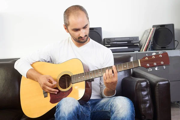 Dospělý člověk hrát na akustickou kytaru v životních domů — Stock fotografie