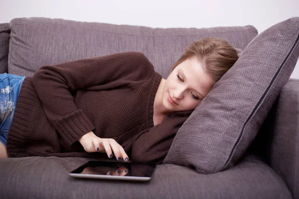 Jovem feliz com tablet pc deitado no sofá — Fotografia de Stock