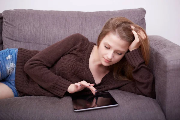 Счастливая молодая женщина с планшетным компьютером на диване — стоковое фото