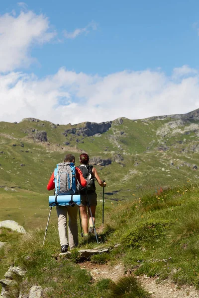 Young people walking down the trail path on mountain. Young couple hiking with backpacks. — Stock Photo, Image