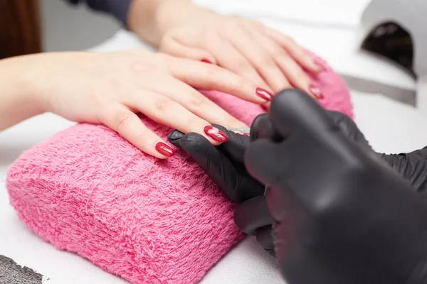 Closeup tiro de um esteticista aplicando esmalte de unhas para unhas femininas em um salão de beleza — Fotografia de Stock