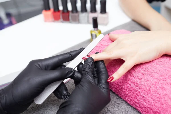 Крупним планом знімок косметолога, який наносить лак для нігтів на жіночий ніготь у нігтьовому салоні — стокове фото