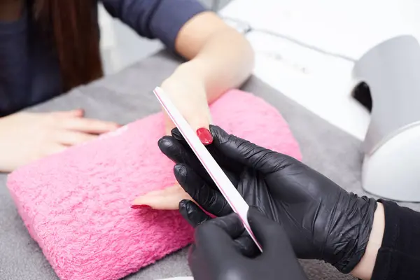 Крупним планом знімок косметолога, який наносить лак для нігтів на жіночий ніготь у нігтьовому салоні — стокове фото