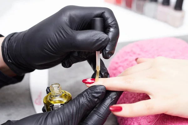 Closeup tiro de um esteticista aplicando esmalte de unhas para unhas femininas em um salão de beleza — Fotografia de Stock