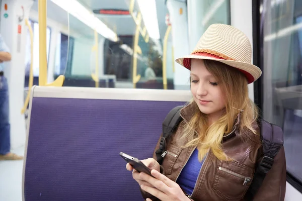 Mosolygó lány használ smartphone metróállomástól vonaton: metro — Stock Fotó