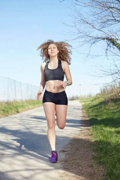 Young attractive sport girl running in park — Stock Photo, Image
