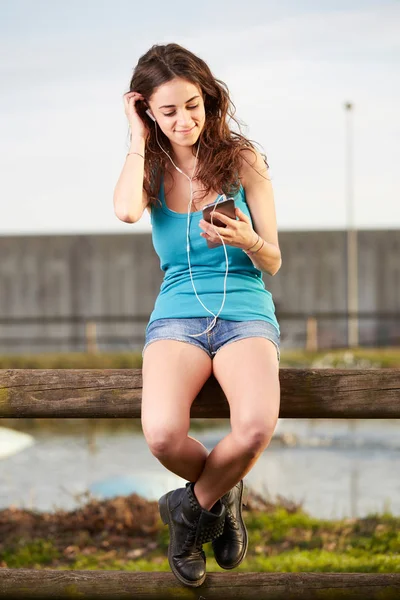 Aantrekkelijke lachende meisje te typen op de mobiele telefoon in de zomer stadspark — Stockfoto