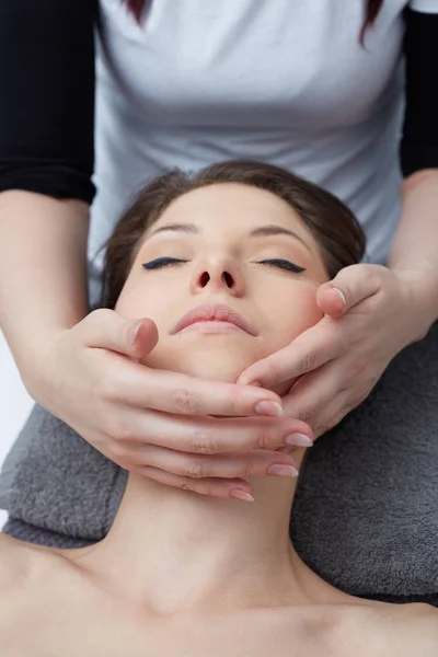 Relaxante bela mulher tendo uma massagem para sua pele em um rosto no salão de beleza — Fotografia de Stock