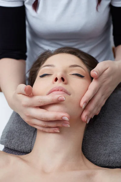 Relaxante bela mulher tendo uma massagem para sua pele em um rosto no salão de beleza — Fotografia de Stock