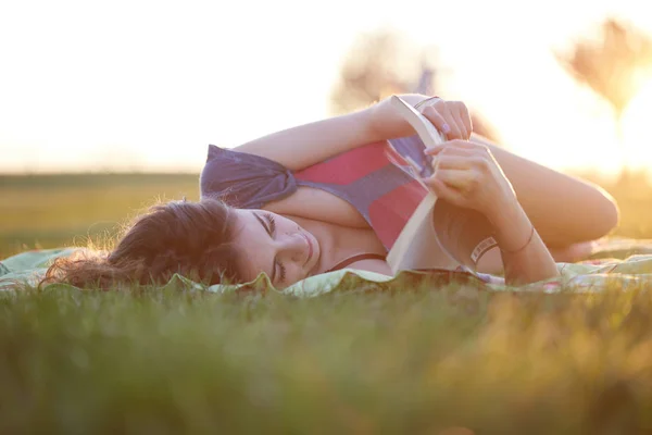 Mulher bonita lendo um livro fora da grama — Fotografia de Stock