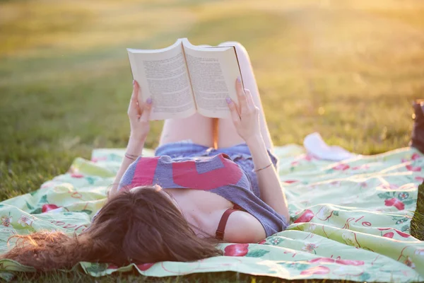 Mulher bonita lendo um livro fora da grama — Fotografia de Stock